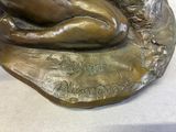 a bronze statue of a woman laying on a rock