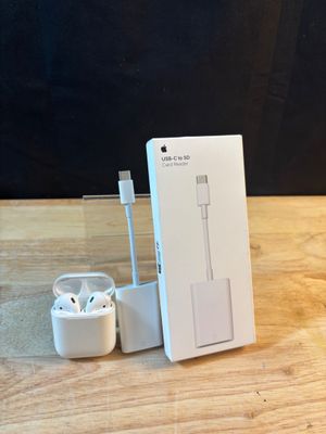 une boîte contenant un chargeur et une paire d'AirPods d'Apple posée sur une table en bois