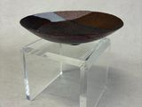un présentoir en acrylique transparent surmonté d'un bol, posé sur une surface blanche
