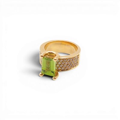 gros plan d'une bague en or avec une pierre verte