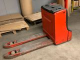 un chariot élévateur rouge dans un entrepôt rempli de cartons