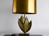 lampe de table en feuille d'or posée sur une table noire, avec un abat-jour doré