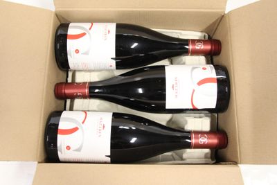 three bottles of red wine in a cardboard box on a table