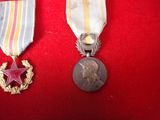 two medals and a star on a red velvet surface