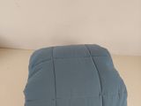 un oreiller bleu posé sur une table blanche