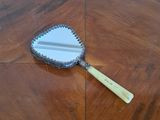 a mirror on the floor with a wooden handle