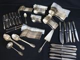 a lot of silverware on a table with a black background