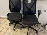 two black office chairs sitting next to each other in a room