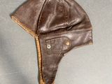 brown leather hat with ear flaps on a gray surface