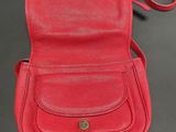 a red leather cross body bag on a black background