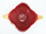 a red bowl with a yellow handle on a white surface