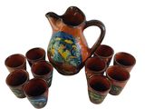 a pitcher and six cups sitting next to each other