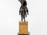 a bronze statue of a man riding a horse on a marble pedestal