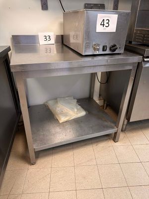 stainless steel table with a microwave on top of it in a kitchen