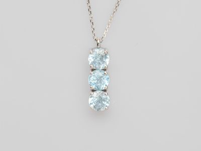 un collier en or blanc orné de trois topazes bleues montées sur une chaîne