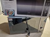 un micro-ondes posé sur un plan de travail, avec une boîte dessus