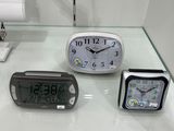 three clocks sitting on a glass table in a room