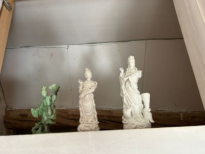 trois statues posées sur une étagère près d'une fenêtre