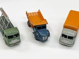 trois camions miniatures posés les uns à côté des autres sur une surface blanche