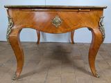 a small wooden table with a marble top on a brick floor