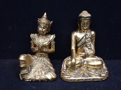 deux statues en or représentant des bouddhas assis sur un socle noir