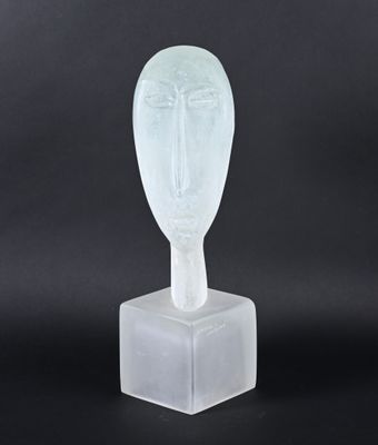 a clear glass sculpture of a face on a block