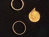 two gold rings and a gold coin are on a black surface
