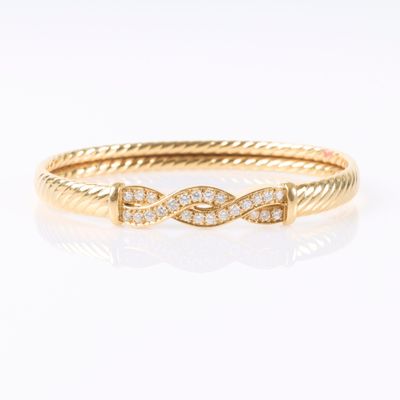 un bracelet rigide en or jaune serti de diamants sur fond blanc