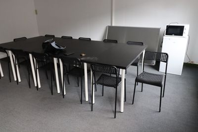 une table et des chaises noires dans une pièce équipée d'un réfrigérateur