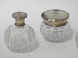 three glass jars with silver lids sitting on top of a white surface