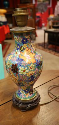 un vase coloré posé sur une table, sur laquelle se trouve une lampe