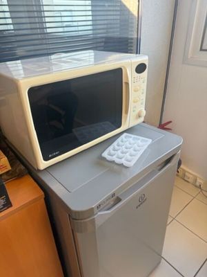 a microwave sitting on top of a refrigerator in a kitchen