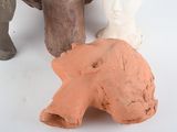 three clay figurines sitting next to each other on a white surface