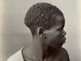 une vieille photo en noir et blanc d'un jeune garçon aux cheveux bouclés