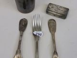 des couverts en argent posés sur une table, accompagnés d'une tasse et d'une cuillère
