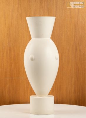 un vase blanc posé sur une table, avec un mur en bois en arrière-plan
