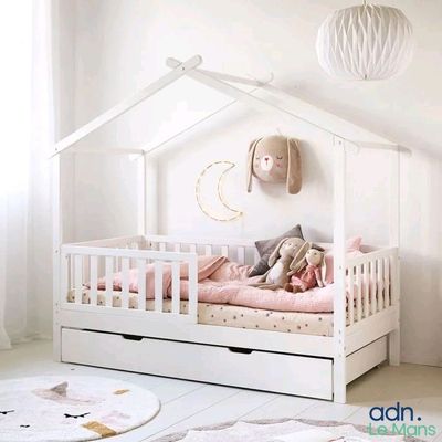 un lit de bébé blanc avec une parure de lit et des oreillers roses