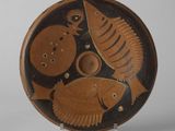 une assiette marron et noire ornée d'un motif de poisson