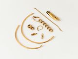 an assortment of gold jewelry on a white surface