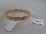 gold bracelet with butterfly design and tag on white surface