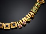 a close up of a gold necklace with multi colored stones