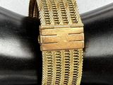 a close up of a gold bracelet on a mannequin arm