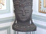 une statue représentant une tête posée sur une table devant un mur