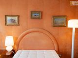 an image of a bedroom with orange walls and a white bed
