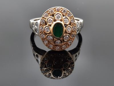 gros plan d'une bague avec une pierre verte entourée de diamants