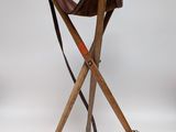 une chaise en bois avec une assise en cuir et deux pieds croisés