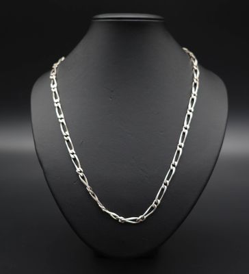 un collier à chaîne en argent autour du cou d'un mannequin