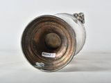 a silver vase sitting on a white surface
