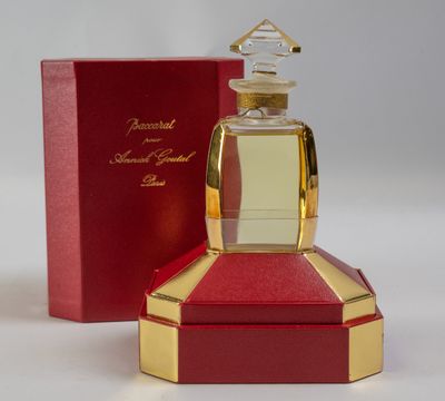 une image représentant un flacon de parfum posé sur une boîte rouge