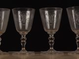 four empty wine glasses lined up on a table against a black background